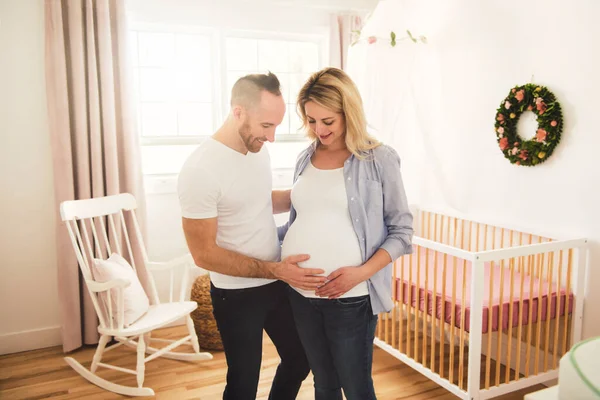 La madre embarazada y su marido en la habitación del bebé en casa — Foto de Stock