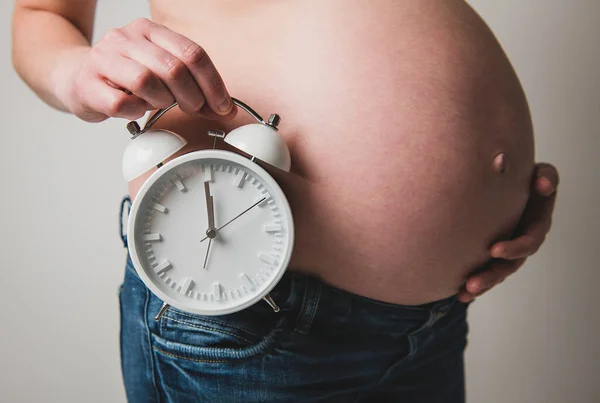 Egy terhes nő, fehér órán elszigetelt órával. — Stock Fotó