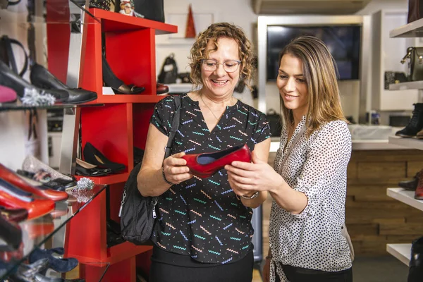 Zapatos nuevos. Compras adicta madre e hija en busca de nuevos zapatos en la nueva sala de exposición —  Fotos de Stock