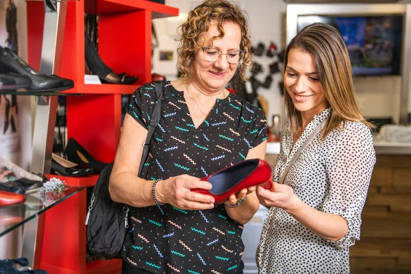 Zapatos nuevos. Compras adicta madre e hija en busca de nuevos zapatos en la nueva sala de exposición —  Fotos de Stock