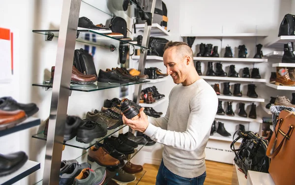 Un hombre está buscando zapatos nuevos en la zapatería. —  Fotos de Stock