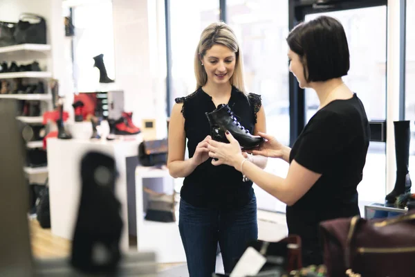 판매자는 여성 고객에게 신발을 신어 보라고 제안 한다 — 스톡 사진