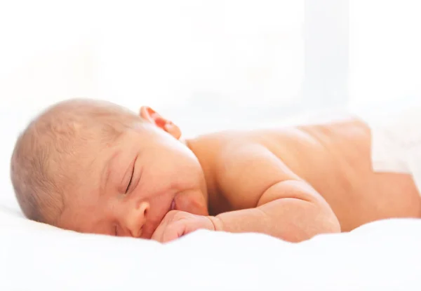 一个新生婴儿躺在柔软的白色背景上睡觉。用这张照片来表现生活、养育子女或童年. — 图库照片