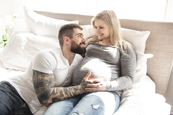 침대에 누워 있는 임신 한 아내의 아기에게 몸을 기대고 있는 남자 — 스톡 사진