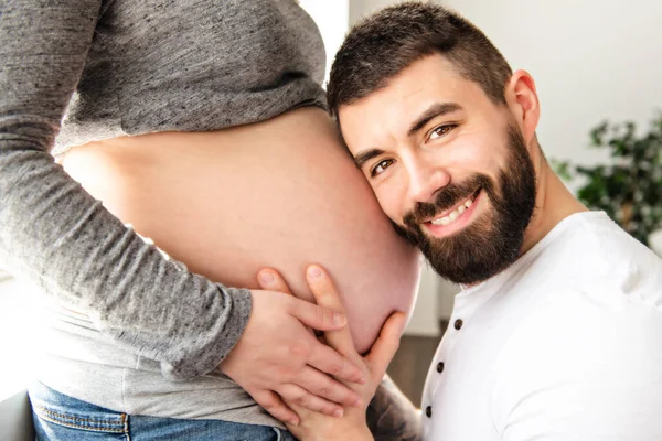 Una bella donna incinta e il suo bel marito guardano da vicino t la pancia — Foto Stock