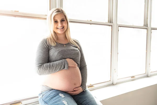 Беременная женщина ласкает живот дома — стоковое фото