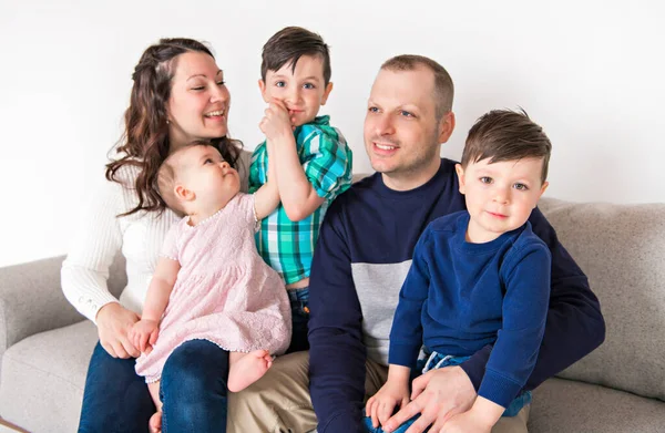 Jong gezin thuis met het kind zitten op de bank — Stockfoto
