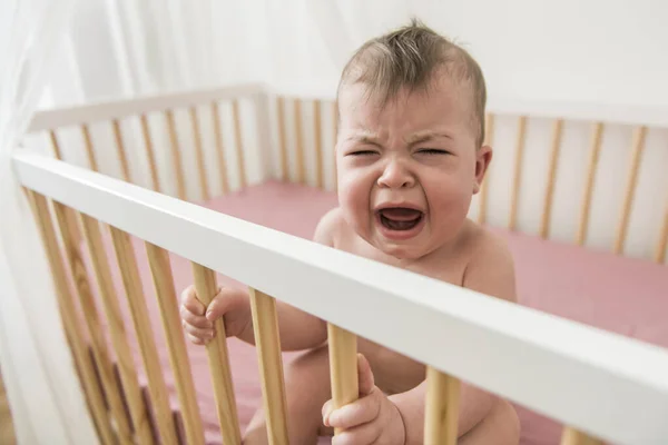 The baby cries and calls mum from a bed — Stock Photo, Image