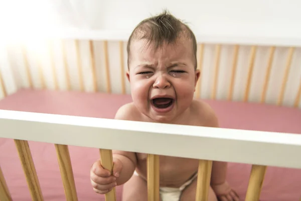 O bebê chora e chama a mãe de uma cama — Fotografia de Stock