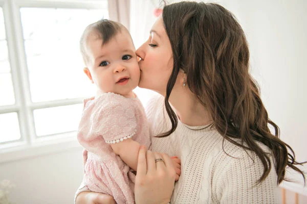 Uma jovem mãe com um bebê em um belo quarto com janela na parte de trás — Fotografia de Stock