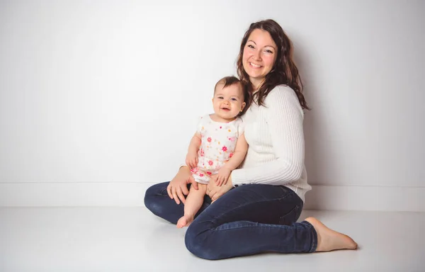 Joven familia madre sobre fondo blanco con el bebé niña —  Fotos de Stock
