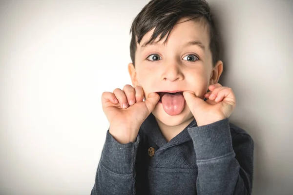 Retrato cercano de un niño de cinco años sobre blanco haciendo sombrío —  Fotos de Stock