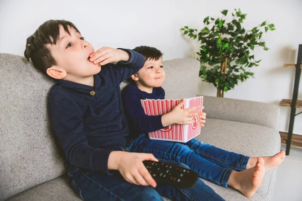 2人の幸せな小さな子供がテレビを見て家でポップコーンを食べて — ストック写真