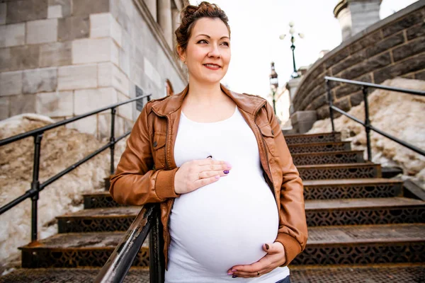 Беременная девушка на улице на ржавой лестнице — стоковое фото
