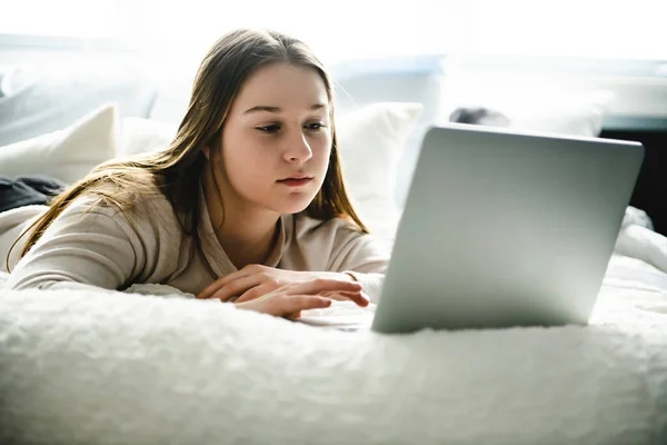 Une jeune adolescente souriante sur le lit avec ordinateur portable — Photo