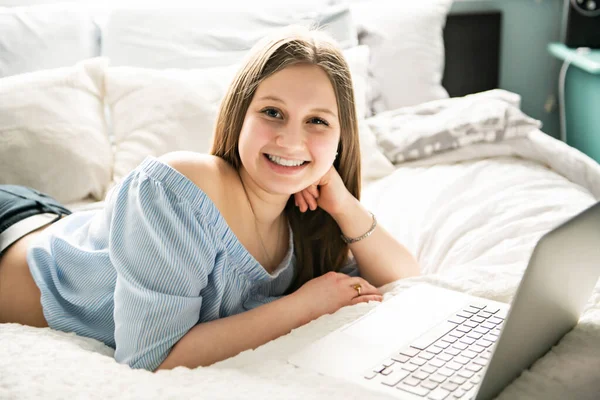 Une jeune adolescente souriante sur le lit avec ordinateur portable — Photo