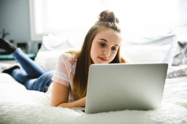 Een jong lachend tiener meisje op bed met laptop — Stockfoto