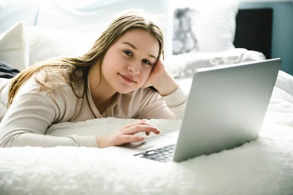 Une jeune adolescente souriante sur le lit avec ordinateur portable — Photo