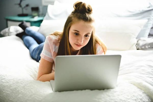 Een jong lachend tiener meisje op bed met laptop — Stockfoto