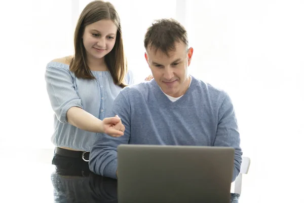 En far som använder en laptop i köket med tonåring — Stockfoto