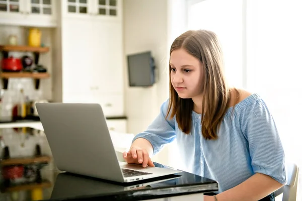 Teenager girl using laptop studying in kitchen — Stock Photo, Image