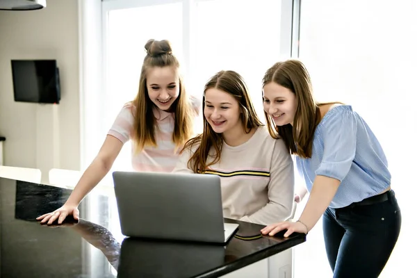 Семья сестра работает за ноутбуком вместе, как они серфинга в социальных сетях или исследования для колледжа опираясь на кухонный счетчик — стоковое фото