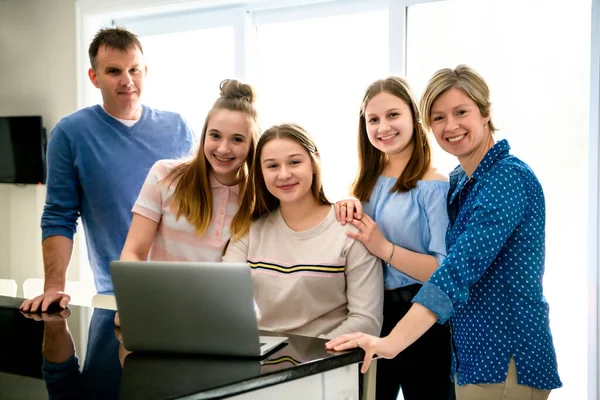 Uma família feliz usando um laptop na cozinha — Fotografia de Stock