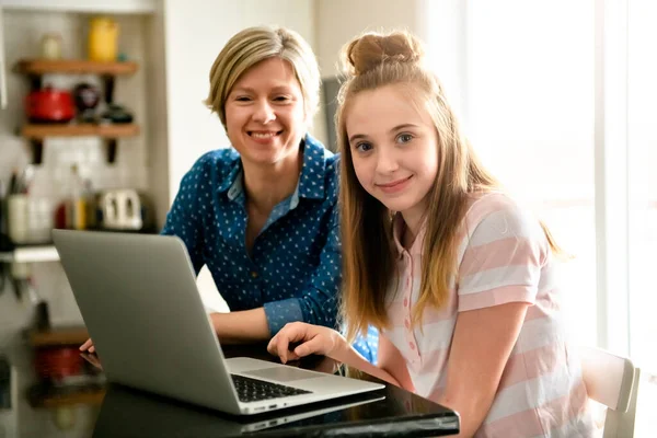 Мати використовує ноутбук на кухні з підлітком — стокове фото