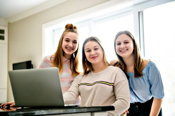 Irmã da família trabalhando em um computador portátil juntos como eles navegar nas mídias sociais ou estudar para a faculdade inclinando-se em um balcão de cozinha — Fotografia de Stock