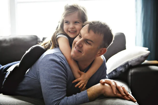 Een leuk en koel kind meisje zittend op vader in de woonkamer — Stockfoto