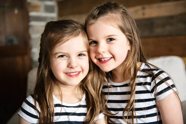 Happy twins embracing each other in the living room — Stock Photo, Image