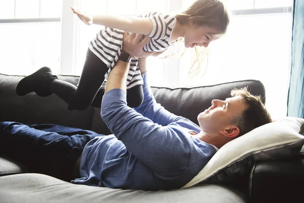 Egy kedves és menő kislány repül apával a nappaliban. — Stock Fotó