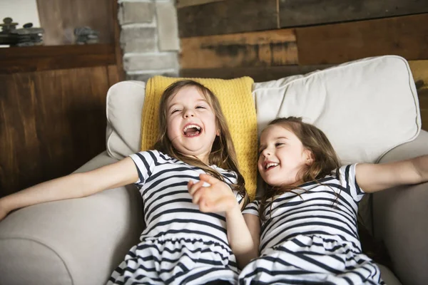 Счастливые близнецы обнимают друг друга в гостиной — стоковое фото