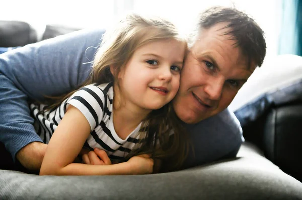 Een leuk en koel kind meisje zittend op vader in de woonkamer — Stockfoto