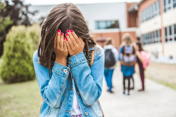 Egy szomorú tinédzser lány az iskolán kívül, diákkal a hátán. — Stock Fotó