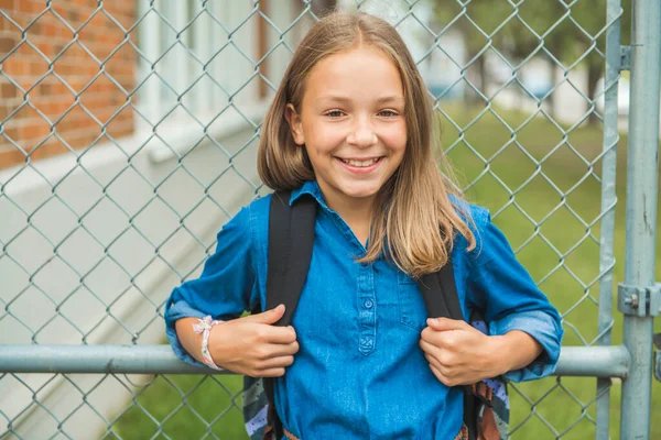 A student school girl on the playground on the first day of class