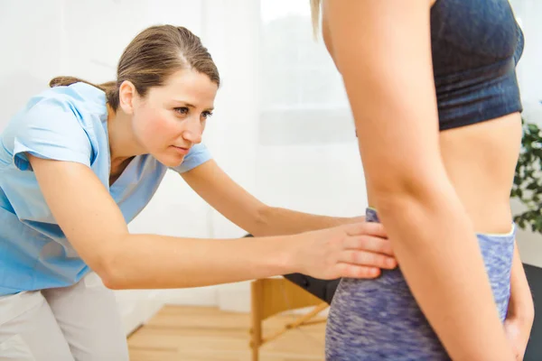 A Modern rehabilitation physiotherapist at work with client. working on lower back. — Stock Photo, Image