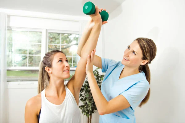 Een moderne revalidatie fysiotherapeut aan het werk met cliënt. Werken op schouder met dumbell — Stockfoto