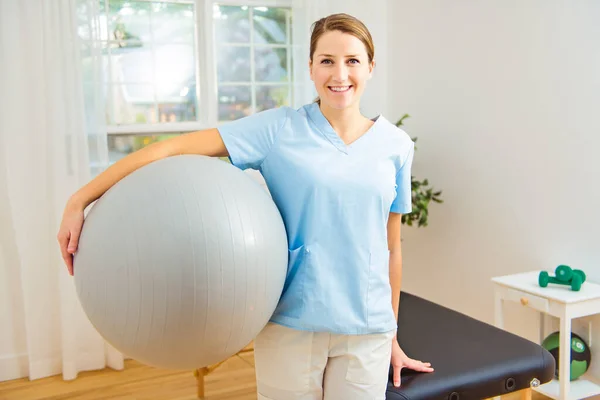 Young physiotherapist with ball in rehabilitation center — Stock Photo, Image