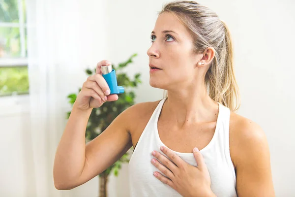 Una mujer joven que usa inhalador de asma en casa — Foto de Stock