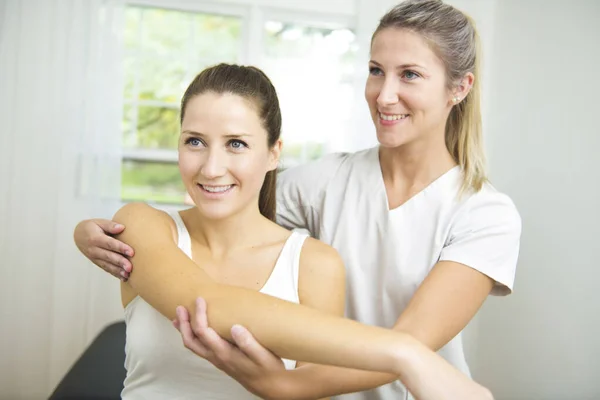 A Modern rehabilitation physiotherapist at work with client. working on shoulder. — Stock Photo, Image