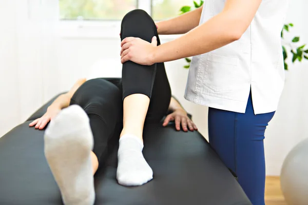 A Modern rehabilitation physiotherapist at work with client. working on knee — Stock Photo, Image