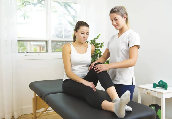 A Modern rehabilitation physiotherapist at work with client. working on knee — Stock Photo, Image