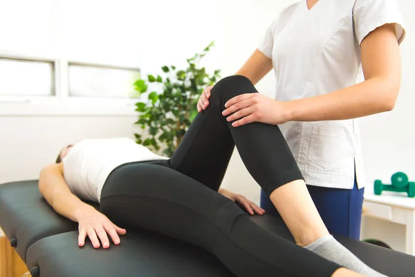 A Modern rehabilitation physiotherapist at work with client. working on knee — Stock Photo, Image