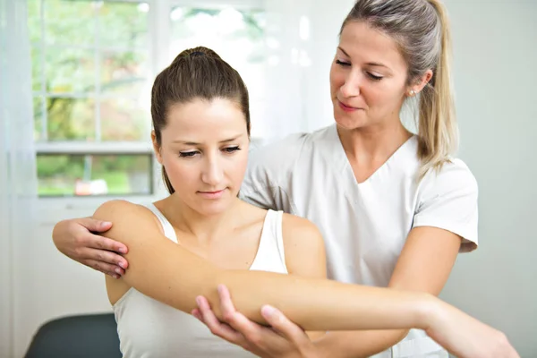 Een moderne revalidatie fysiotherapeut aan het werk met cliënt. werken op de schouder. — Stockfoto