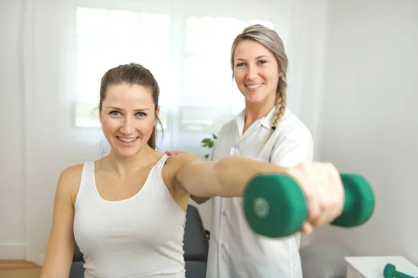 Un fisioterapeuta de rehabilitación moderna en el trabajo con el cliente. Trabajar en hombro con mancuernas — Foto de Stock