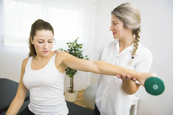 Un fisioterapeuta de rehabilitación moderna en el trabajo con el cliente. Trabajar en hombro con mancuernas — Foto de Stock