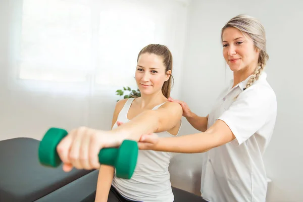 Fisioterapis rehabilitasi modern bekerja dengan klien. Bekerja di bahu dengan dumbell — Stok Foto