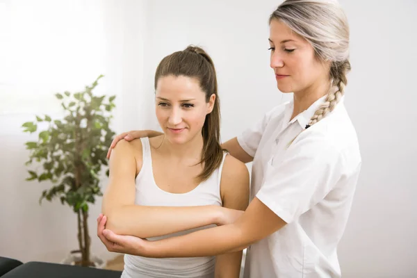 Um fisioterapeuta de reabilitação moderna no trabalho com o cliente — Fotografia de Stock