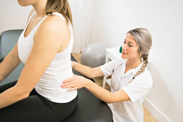 A Modern rehabilitation physiotherapist at work with client. working on lower back. — Stock Photo, Image